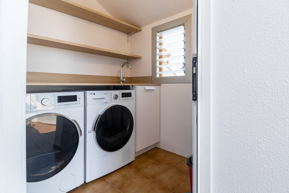 This is an example of a small scandinavian single-wall laundry cupboard in Other with a drop-in sink, flat-panel cabinets, white cabinets, laminate benchtops, white walls, ceramic floors, a side-by-side washer and dryer, brown floor and brown benchtop.