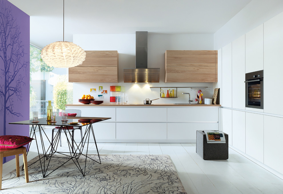 Design ideas for a contemporary eat-in kitchen in Toulouse with a drop-in sink, flat-panel cabinets, white cabinets, stainless steel appliances, painted wood floors, no island and white floor.