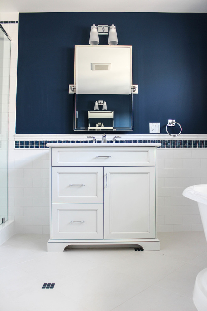 Photo of a mid-sized beach style master bathroom in New York with a pedestal sink, beaded inset cabinets, marble benchtops, a claw-foot tub, an alcove shower, a one-piece toilet, beige tile, ceramic tile, white walls, porcelain floors and white cabinets.