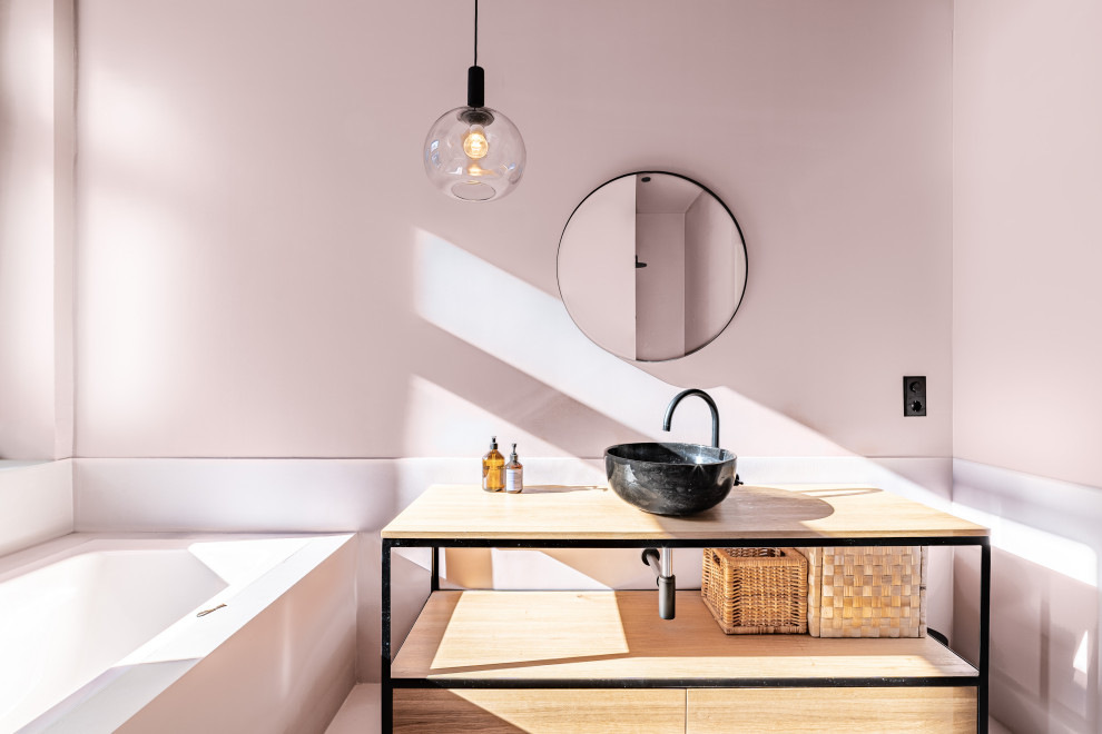 Cette photo montre une salle de bain moderne avec une baignoire posée, un sol rose et meuble simple vasque.