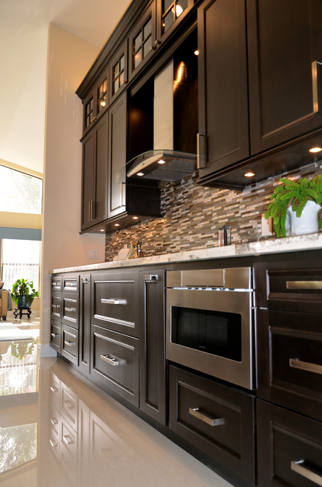 Open concept kitchen - large transitional l-shaped porcelain tile open concept kitchen idea in Miami with an undermount sink, recessed-panel cabinets, dark wood cabinets, granite countertops, multicolored backsplash, mosaic tile backsplash, stainless steel appliances and an island