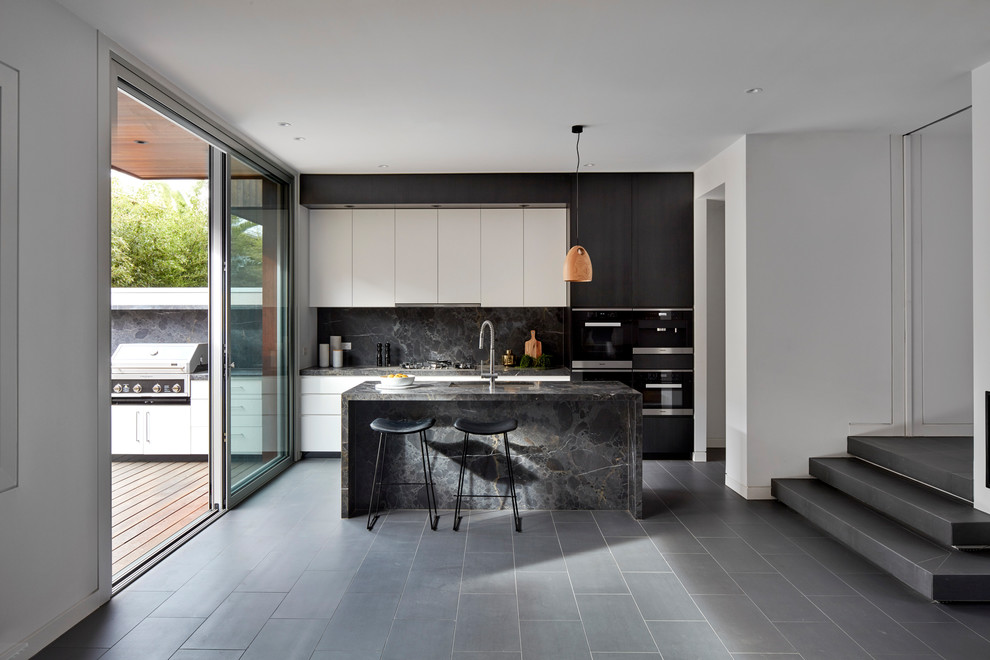 This is an example of a mid-sized contemporary open plan kitchen in Melbourne with an undermount sink, flat-panel cabinets, dark wood cabinets, marble benchtops, grey splashback, marble splashback, black appliances, porcelain floors, with island, black floor and grey benchtop.
