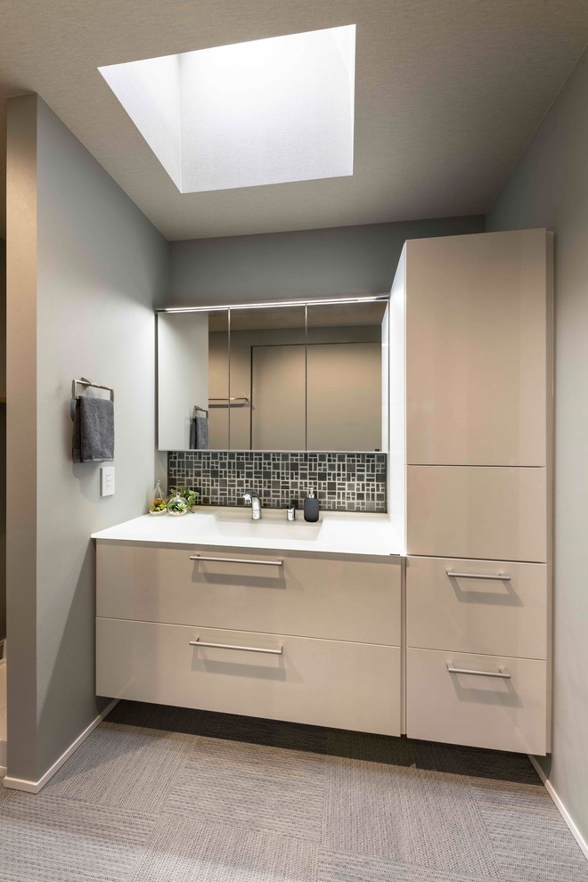 Photo of a mid-sized modern powder room in Other with flat-panel cabinets, white cabinets, gray tile, grey walls, an integrated sink, solid surface benchtops, grey floor and white benchtops.