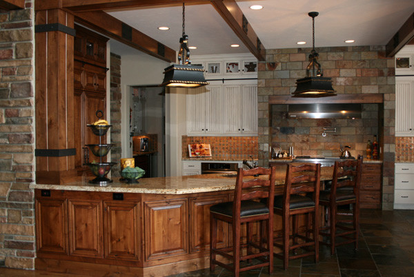 This is an example of a large country u-shaped eat-in kitchen in Denver with an undermount sink, raised-panel cabinets, medium wood cabinets, granite benchtops, multi-coloured splashback, stone tile splashback, panelled appliances, slate floors and a peninsula.