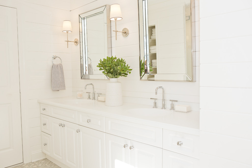 Small beach style master bathroom in New York with raised-panel cabinets, white cabinets, a drop-in tub, a shower/bathtub combo, a one-piece toilet, white tile, marble, white walls, cement tiles, an undermount sink, marble benchtops, grey floor and a hinged shower door.