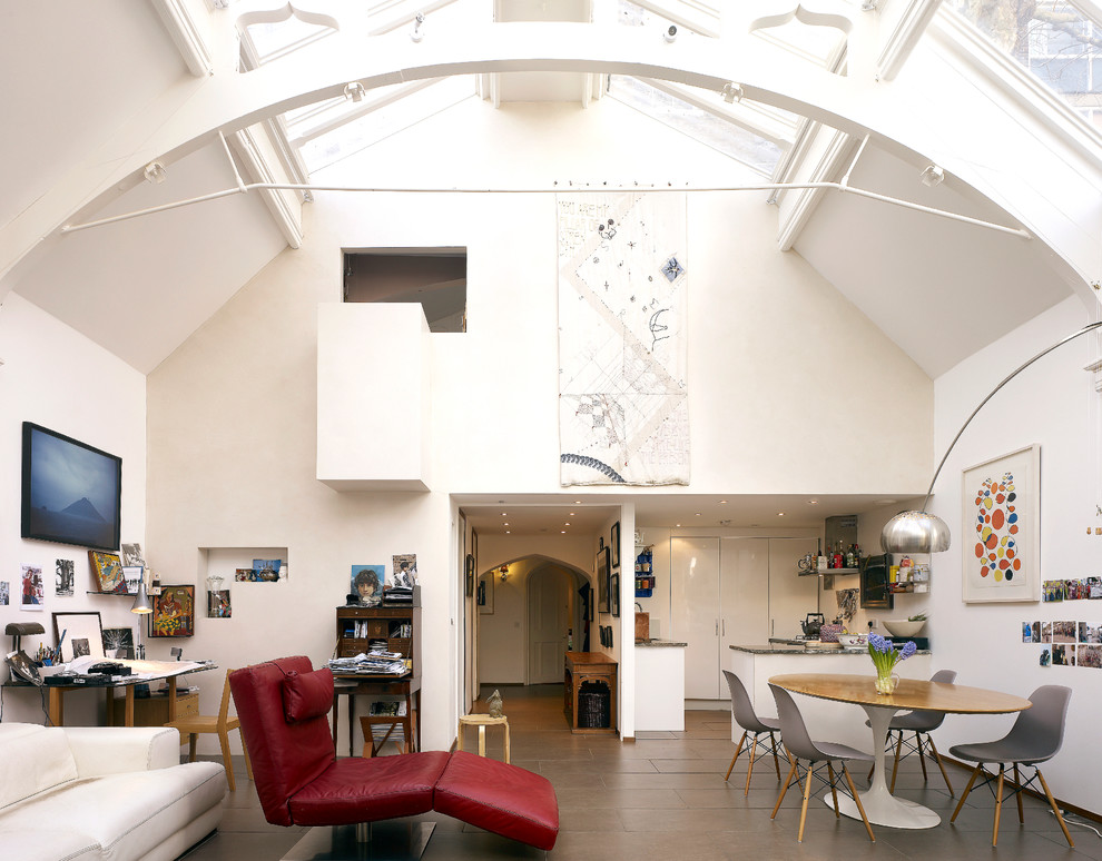 This is an example of a large eclectic open plan dining in London with white walls and porcelain floors.