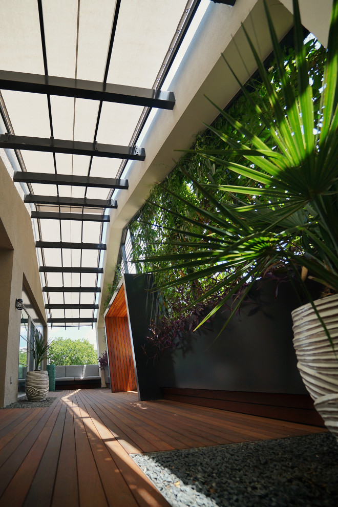 Foto de patio moderno de tamaño medio en patio con jardín vertical, entablado y toldo