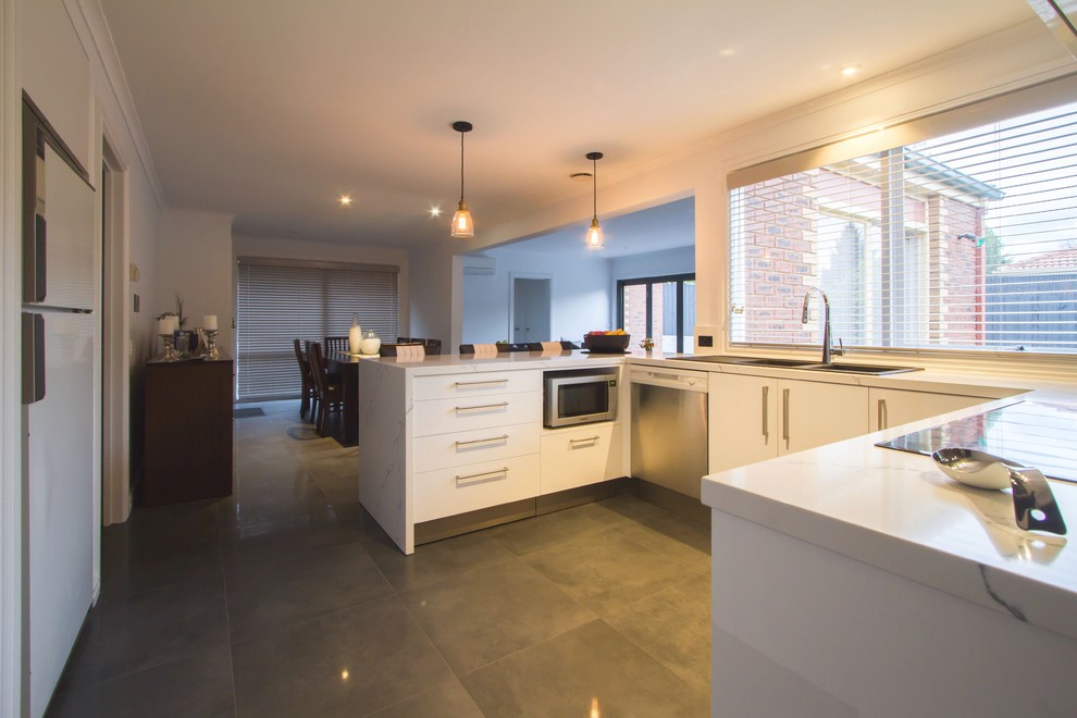 Mid-sized contemporary u-shaped eat-in kitchen in Melbourne with a drop-in sink, flat-panel cabinets, white cabinets, quartz benchtops, mirror splashback and a peninsula.