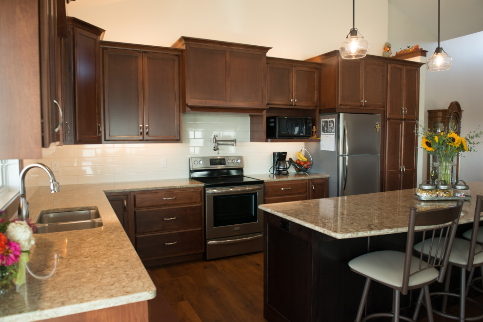 Large transitional l-shaped medium tone wood floor open concept kitchen photo with an undermount sink, flat-panel cabinets, medium tone wood cabinets, quartz countertops, white backsplash, ceramic backsplash, stainless steel appliances, an island and multicolored countertops