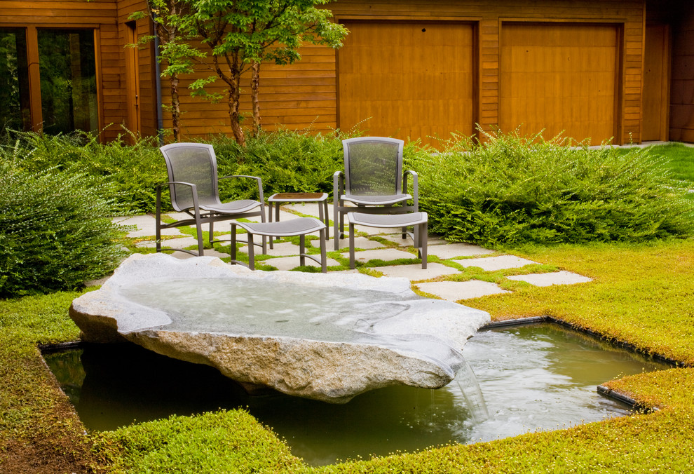 This is an example of a contemporary garden in Seattle with a water feature.