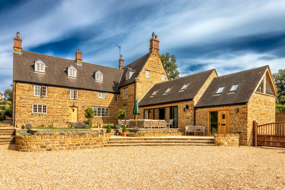 Example of a small trendy beige one-story stone exterior home design in Oxfordshire with a shingle roof and a brown roof