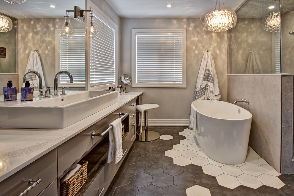 Inspiration for a transitional master bathroom in Toronto with grey cabinets, a freestanding tub, gray tile, white tile, porcelain tile, grey walls, porcelain floors, a vessel sink, engineered quartz benchtops and a corner shower.