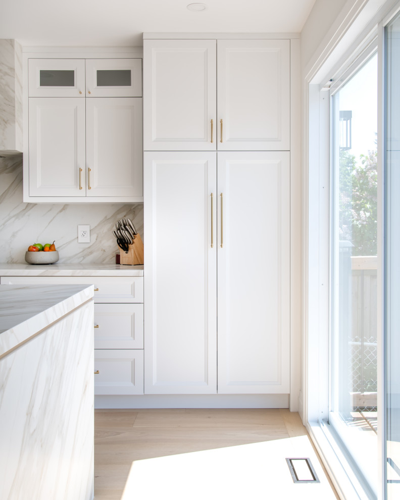 Inspiration for a mid-sized transitional galley light wood floor and beige floor open concept kitchen remodel in Ottawa with an undermount sink, recessed-panel cabinets, white cabinets, quartz countertops, white backsplash, porcelain backsplash, stainless steel appliances, an island and white countertops