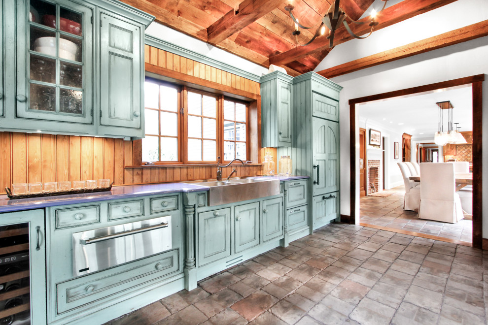 Mid-sized mountain style single-wall gray floor and vaulted ceiling kitchen photo in New York with a farmhouse sink, raised-panel cabinets, turquoise cabinets, brown backsplash, wood backsplash and blue countertops