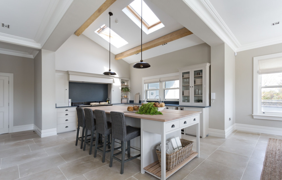 Design ideas for a beach style l-shaped open plan kitchen in Dublin with a farmhouse sink, shaker cabinets, beige cabinets, soapstone benchtops, with island, black benchtop and exposed beam.