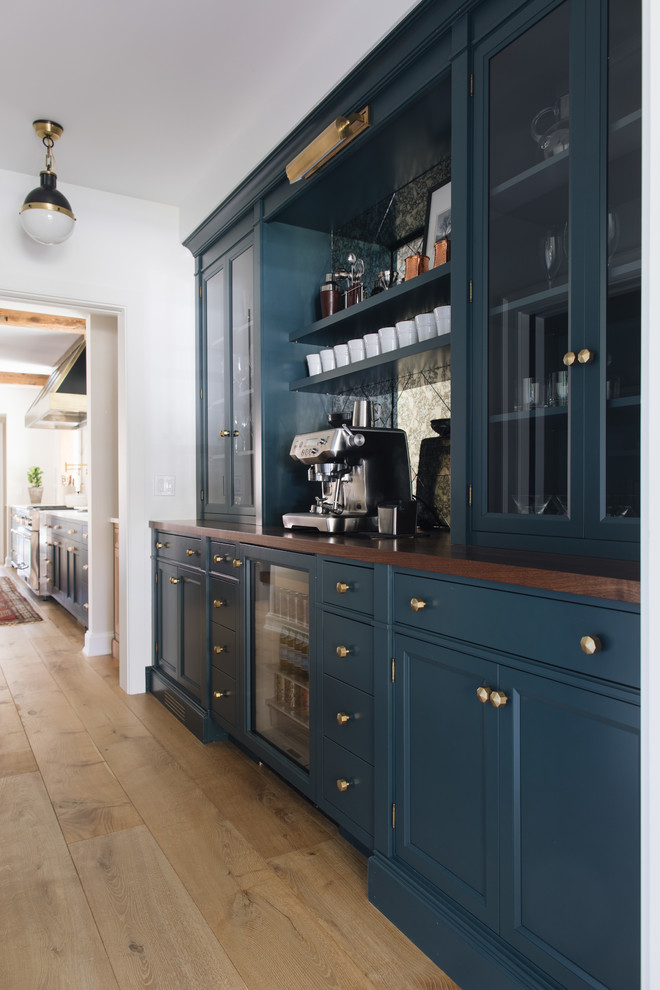 Inspiration for a mid-sized transitional single-wall home bar in Grand Rapids with recessed-panel cabinets, blue cabinets, wood benchtops, medium hardwood floors and brown floor.