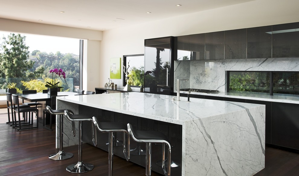 This is an example of a modern galley eat-in kitchen in Los Angeles with flat-panel cabinets, black cabinets, marble benchtops, white splashback, stone slab splashback and panelled appliances.