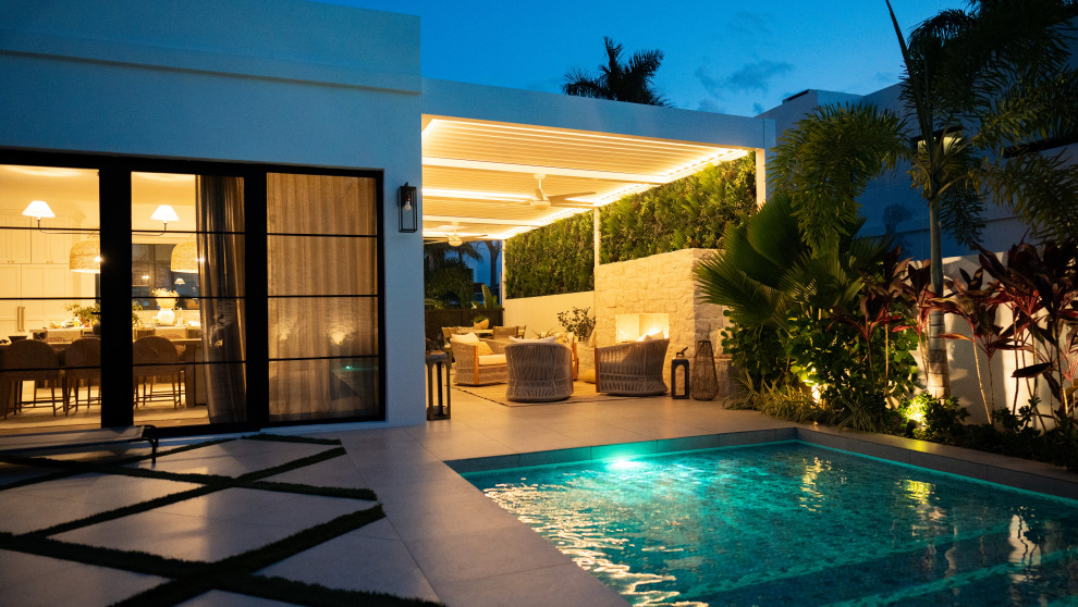 Immagine di un patio o portico tropicale di medie dimensioni e dietro casa con pavimentazioni in pietra naturale e una pergola