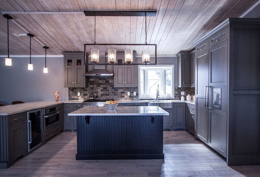 Eat-in kitchen - mid-sized transitional u-shaped light wood floor eat-in kitchen idea in Chicago with a farmhouse sink, flat-panel cabinets, green cabinets, quartzite countertops, multicolored backsplash, stone tile backsplash, paneled appliances and an island
