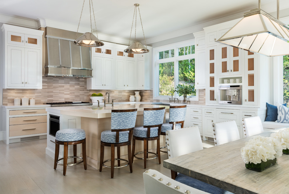 Inspiration for a beach style l-shaped eat-in kitchen in Hawaii with white cabinets, beige splashback, matchstick tile splashback, light hardwood floors and with island.