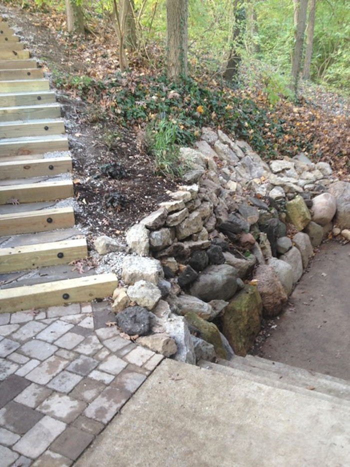 Photo of a large shade backyard stone retaining wall landscape.