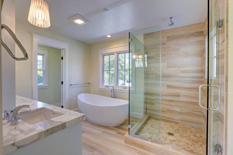 This is an example of a mid-sized country master bathroom in San Francisco with shaker cabinets, white cabinets, a freestanding tub, an open shower, a one-piece toilet, white tile, porcelain tile, white walls, porcelain floors, an undermount sink, marble benchtops, brown floor, a hinged shower door, white benchtops, a double vanity and a built-in vanity.