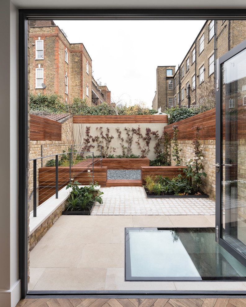 Photo of a mid-sized contemporary three-storey brick townhouse exterior in London with a flat roof and a green roof.