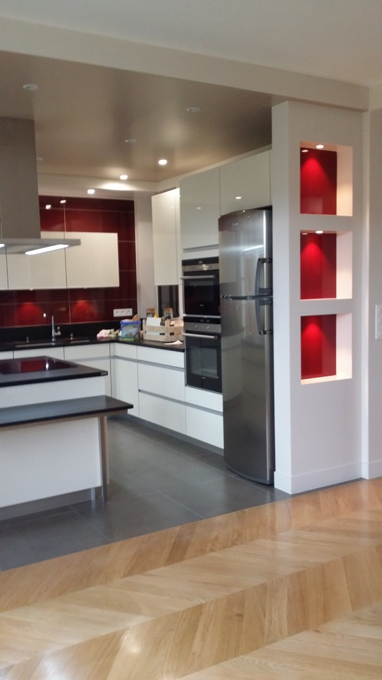 Photo of a large contemporary l-shaped open plan kitchen in Paris with an undermount sink, beige cabinets, granite benchtops, red splashback, panelled appliances, ceramic floors and with island.