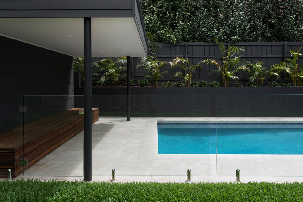 Contemporary backyard rectangular pool with tile.
