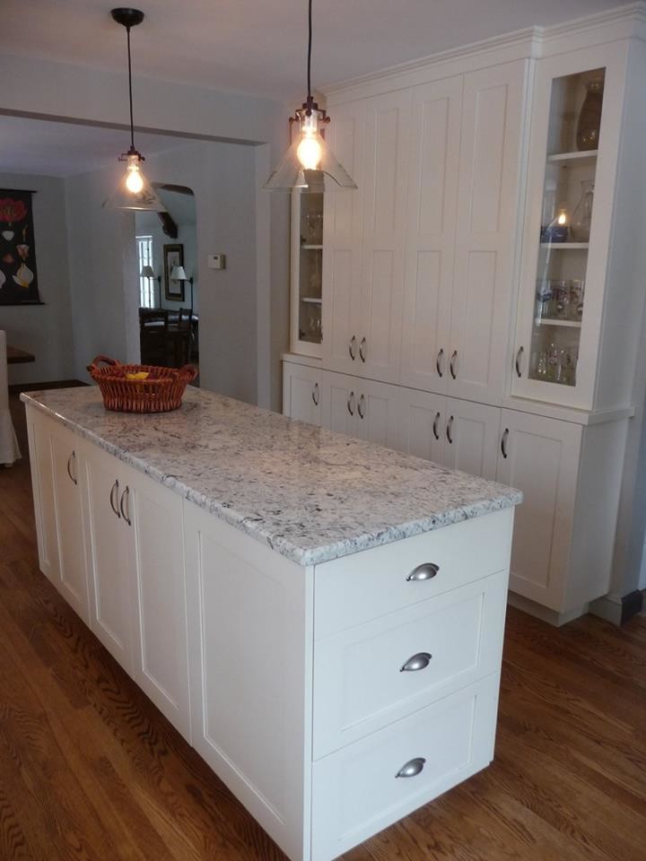 Large transitional u-shaped light wood floor home design photo in Milwaukee with a farmhouse sink, recessed-panel cabinets, white cabinets, granite countertops, gray backsplash, subway tile backsplash, stainless steel appliances and an island