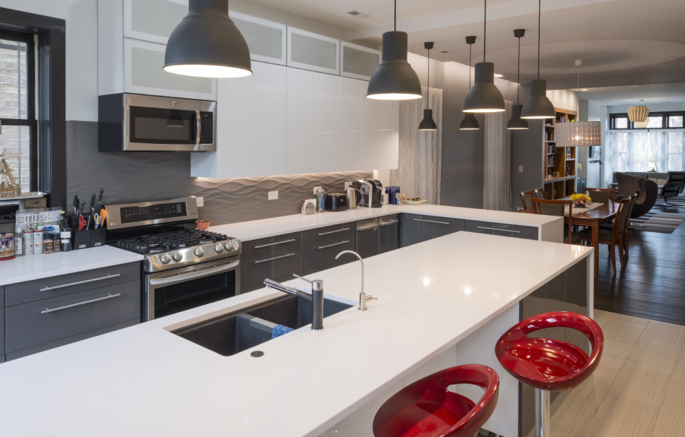 Mid-sized trendy l-shaped porcelain tile and beige floor open concept kitchen photo in Chicago with an undermount sink, flat-panel cabinets, gray cabinets, quartz countertops, white backsplash, porcelain backsplash, stainless steel appliances, an island and white countertops
