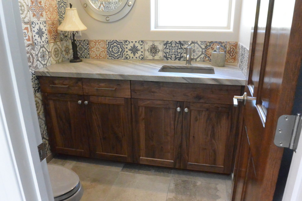 Huge transitional l-shaped porcelain tile and gray floor open concept kitchen photo with an undermount sink, shaker cabinets, medium tone wood cabinets, quartzite countertops, white backsplash, porcelain backsplash, paneled appliances, an island and green countertops