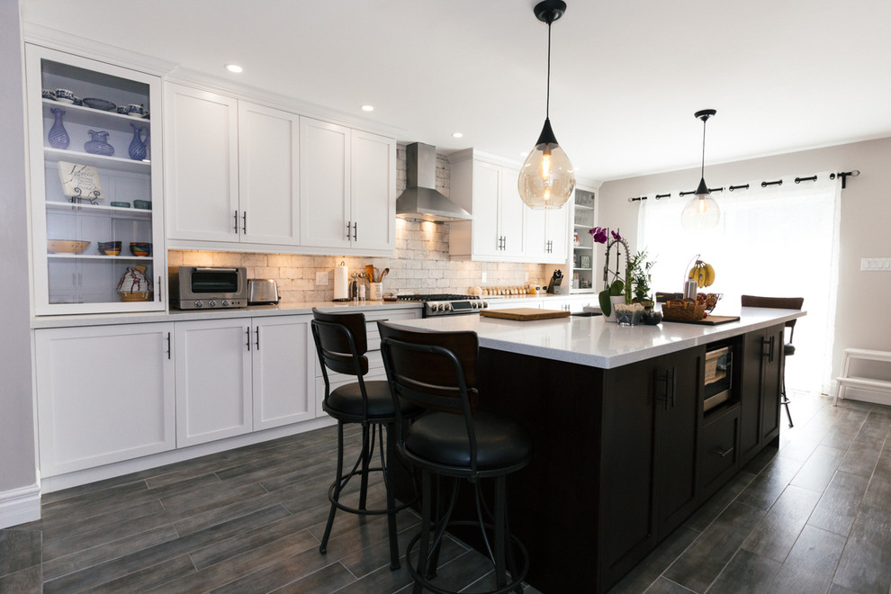 Example of a large transitional single-wall dark wood floor enclosed kitchen design in Toronto with a farmhouse sink, shaker cabinets, white cabinets, granite countertops, white backsplash, stone tile backsplash, stainless steel appliances and an island