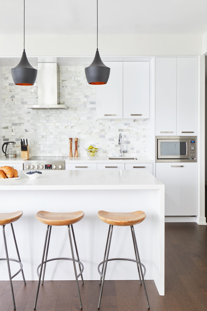 Photo of a scandinavian kitchen in Toronto with an undermount sink, flat-panel cabinets, white cabinets, multi-coloured splashback, stainless steel appliances, dark hardwood floors, with island, brown floor, white benchtop and marble splashback.