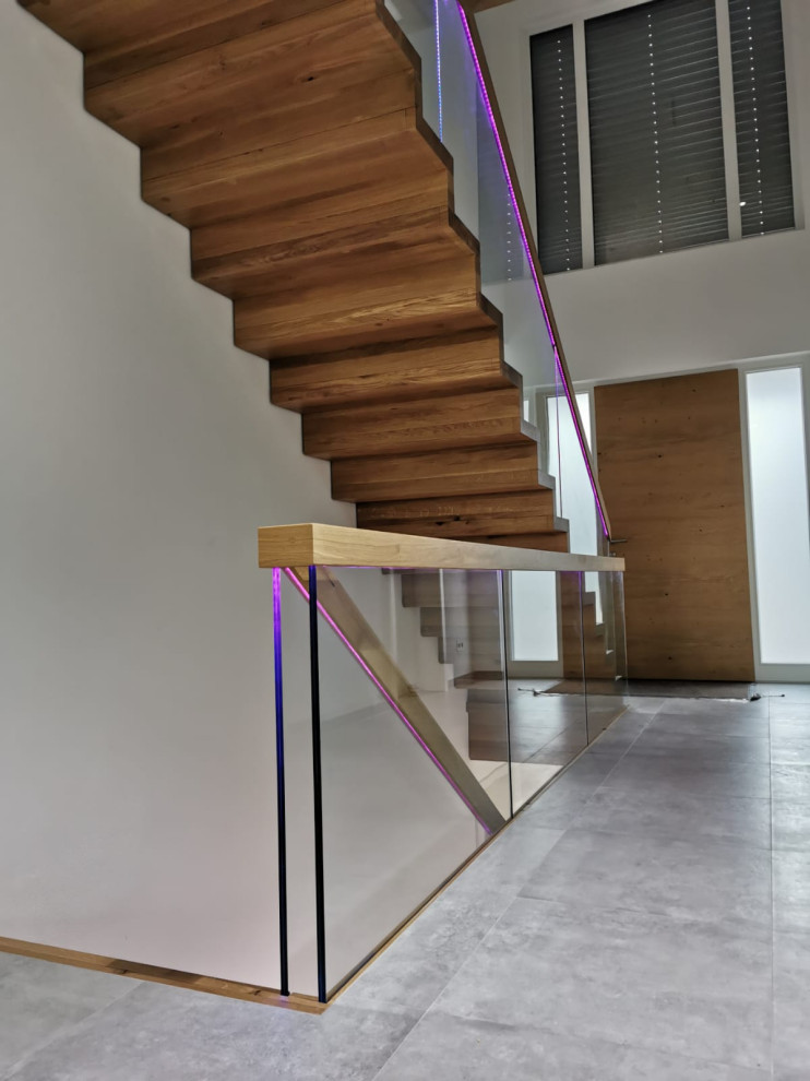 This is an example of an expansive modern wood straight glass railing staircase in Other with wood risers and brick walls.