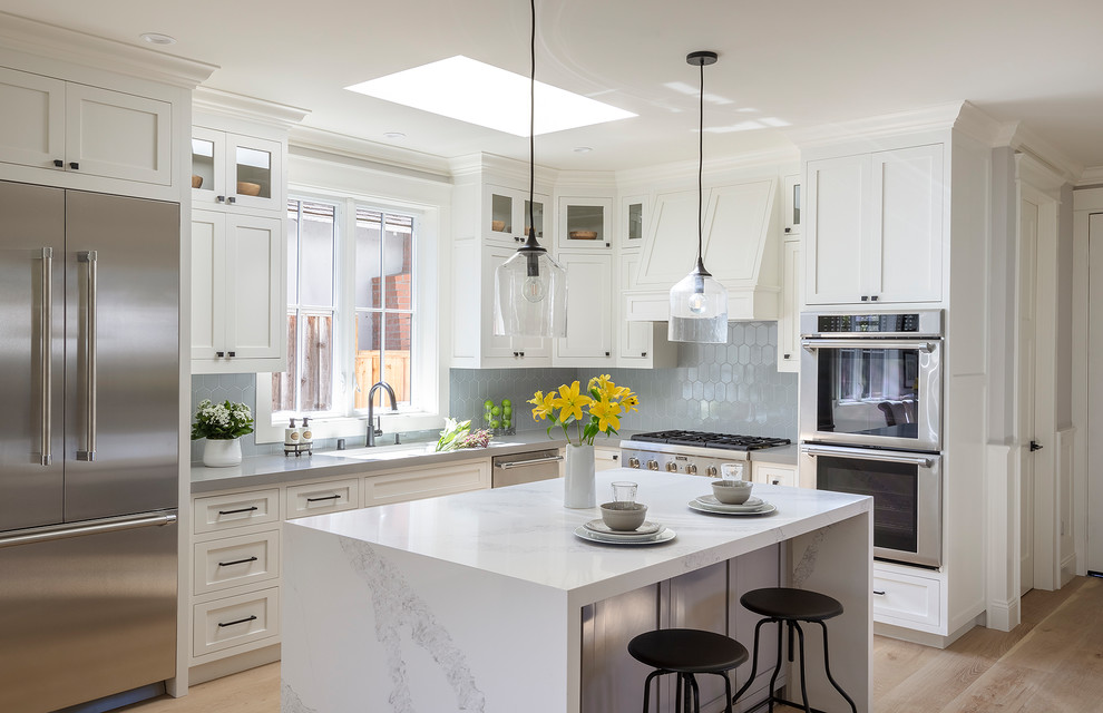 Small country l-shaped open plan kitchen in San Francisco with an undermount sink, shaker cabinets, white cabinets, quartz benchtops, blue splashback, ceramic splashback, stainless steel appliances, light hardwood floors, with island, grey floor and grey benchtop.