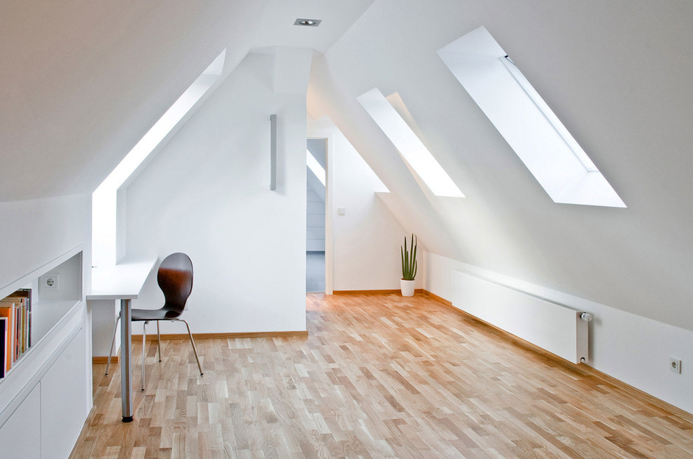 Mid-sized contemporary study room in Dortmund with white walls, light hardwood floors and a built-in desk.