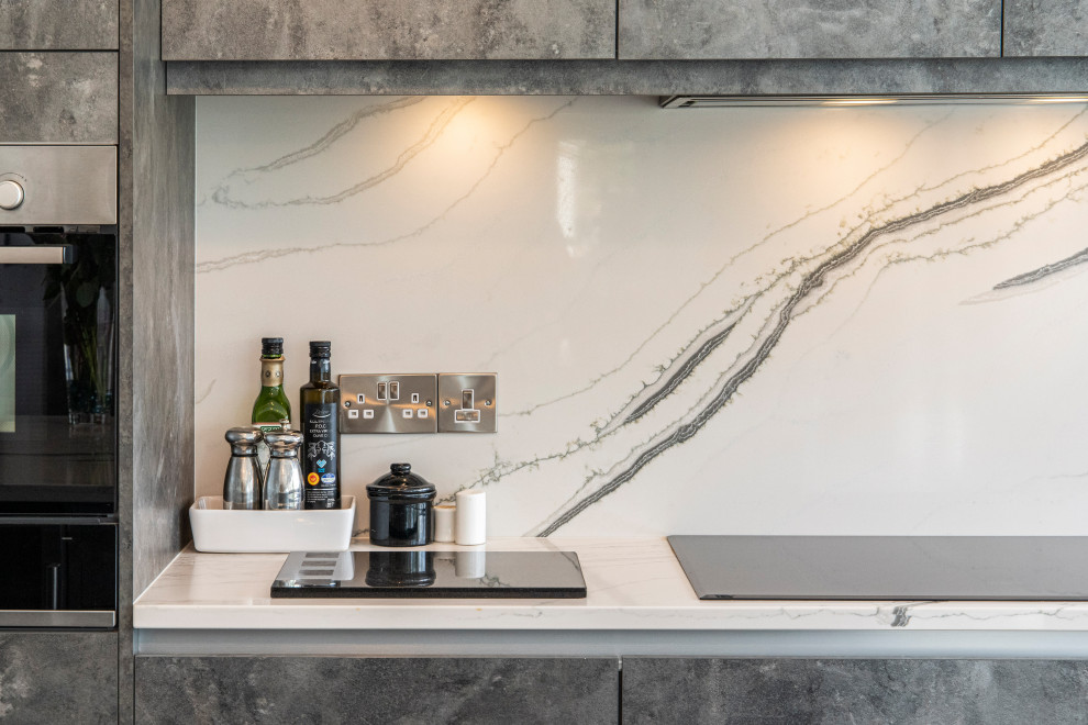 Design ideas for a large modern u-shaped eat-in kitchen in Cornwall with a drop-in sink, flat-panel cabinets, grey cabinets, quartzite benchtops, white splashback, engineered quartz splashback, panelled appliances, porcelain floors, with island, beige floor and white benchtop.
