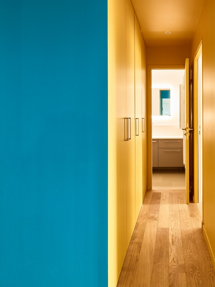 Idée de décoration pour un couloir design de taille moyenne avec un mur jaune, un sol en bois brun et un sol marron.