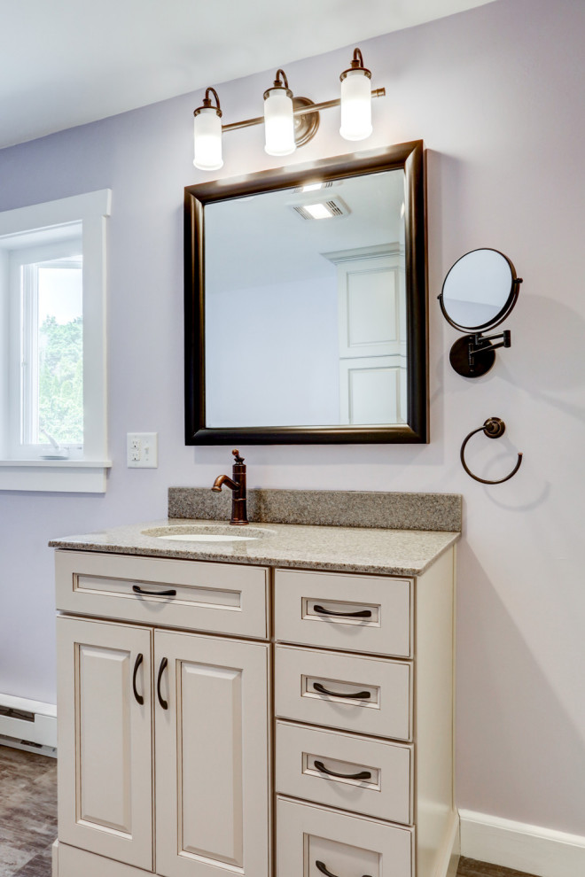This is an example of a mid-sized arts and crafts master bathroom in Other with beige cabinets, a freestanding tub, an alcove shower, purple walls, vinyl floors, an undermount sink, marble benchtops, brown floor, a hinged shower door, beige benchtops, a single vanity and a freestanding vanity.