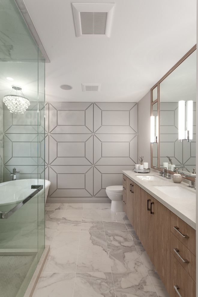 Design ideas for a mid-sized contemporary master bathroom in Vancouver with flat-panel cabinets, a freestanding tub, grey walls, an undermount sink, a corner shower, marble floors, white floor, a sliding shower screen, medium wood cabinets, marble and solid surface benchtops.