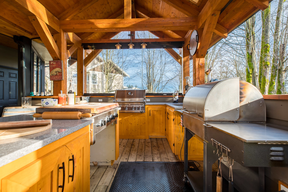 Example of a large mountain style backyard outdoor kitchen deck design in Vancouver with a roof extension