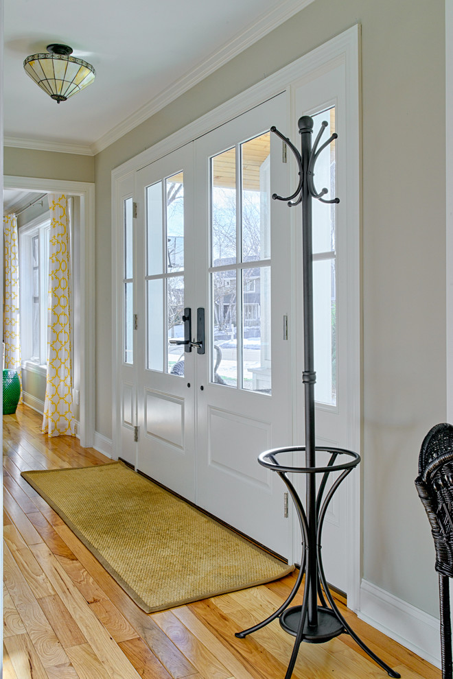 This is an example of a mid-sized transitional front door in Minneapolis with beige walls, light hardwood floors, a double front door and a white front door.
