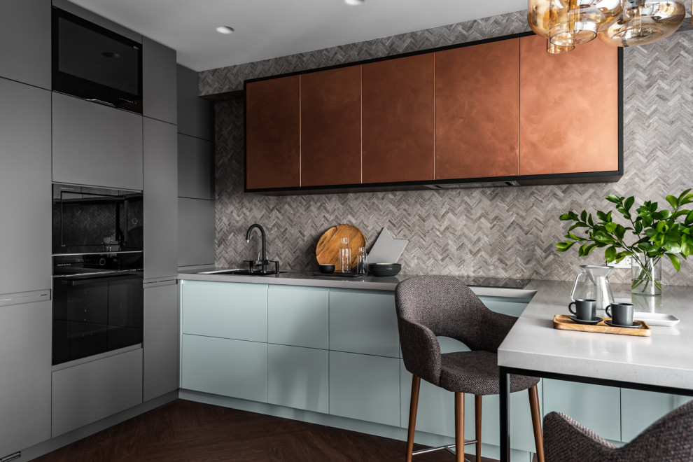 This is an example of a small contemporary u-shaped eat-in kitchen in Yekaterinburg with a single-bowl sink, flat-panel cabinets, solid surface benchtops, multi-coloured splashback, mosaic tile splashback, black appliances, vinyl floors, a peninsula, beige floor, grey benchtop and blue cabinets.