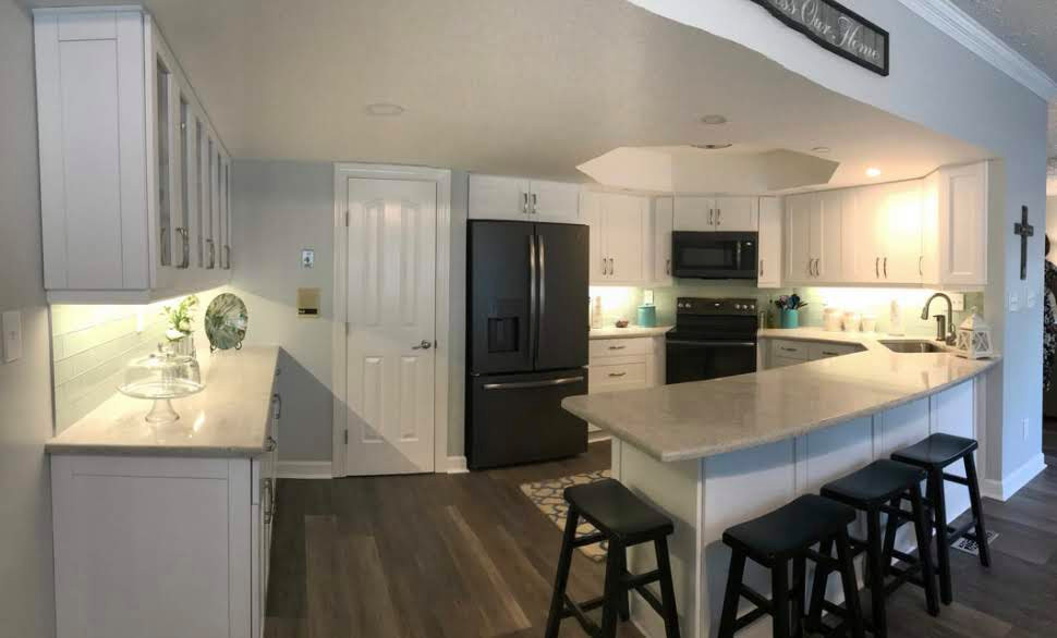 Example of a mid-sized transitional u-shaped dark wood floor, brown floor and tray ceiling kitchen pantry design with an undermount sink, recessed-panel cabinets, white cabinets, granite countertops, green backsplash, ceramic backsplash, black appliances, a peninsula and gray countertops