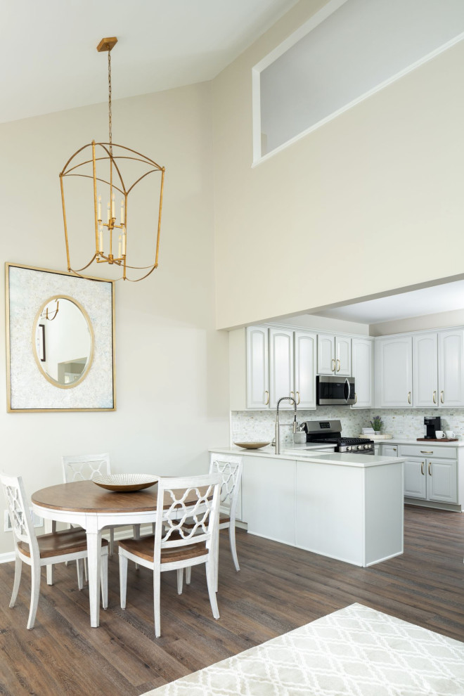 Inredning av ett klassiskt avskilt, litet vit vitt u-kök, med en undermonterad diskho, luckor med upphöjd panel, grå skåp, bänkskiva i kvarts, vitt stänkskydd, stänkskydd i marmor, rostfria vitvaror, vinylgolv, en halv köksö och brunt golv
