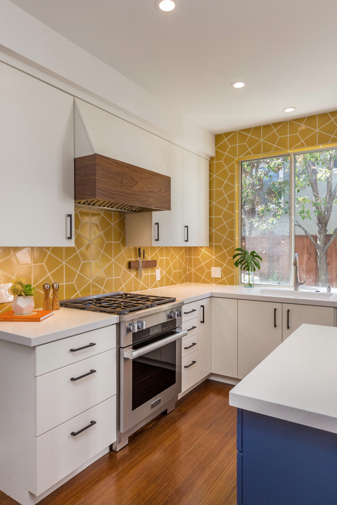 Inspiration for a mid-sized midcentury u-shaped eat-in kitchen in San Francisco with an undermount sink, flat-panel cabinets, white cabinets, quartz benchtops, yellow splashback, ceramic splashback, stainless steel appliances, medium hardwood floors, with island, brown floor, white benchtop and timber.