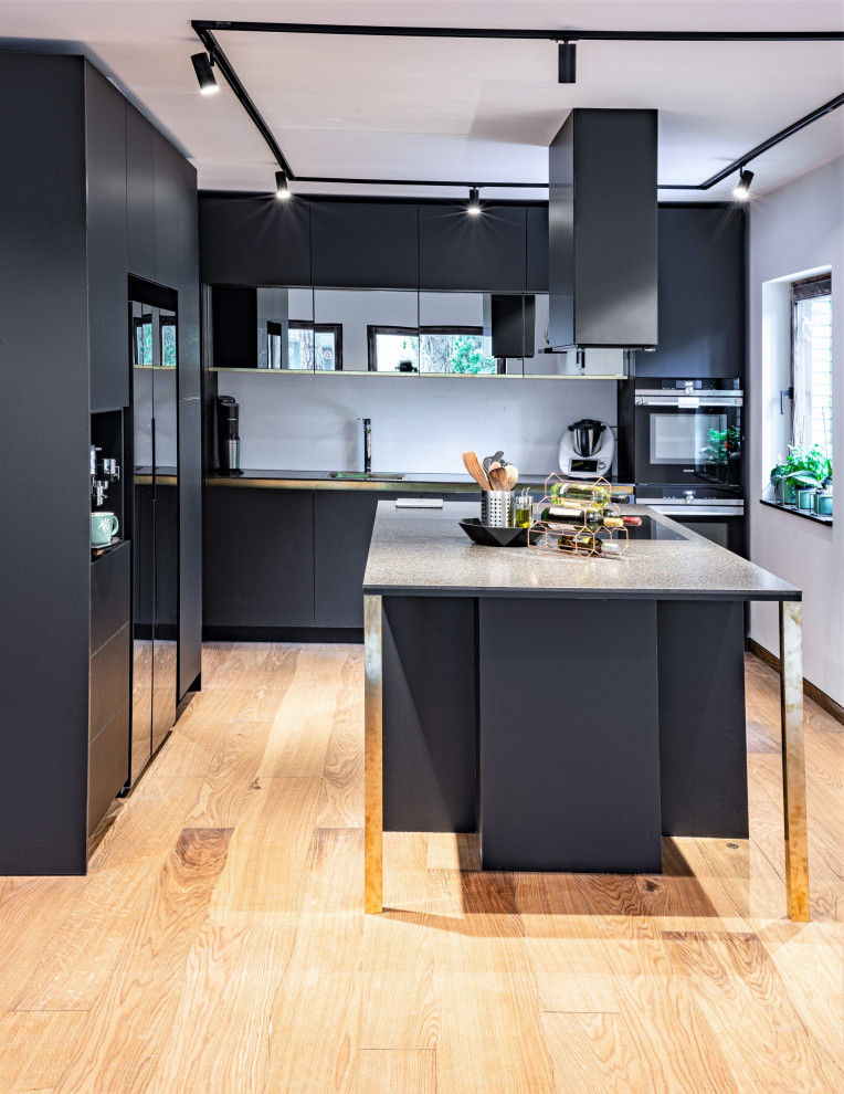 Idées déco pour une cuisine ouverte contemporaine de taille moyenne avec un plan de travail en surface solide, un électroménager noir, un sol en bois brun et îlot.