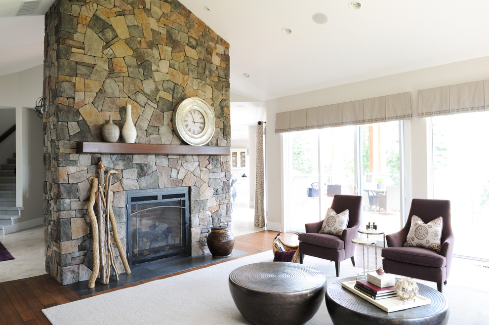 Photo of a large beach style open concept living room in Vancouver with beige walls, medium hardwood floors, a standard fireplace, a stone fireplace surround and a built-in media wall.