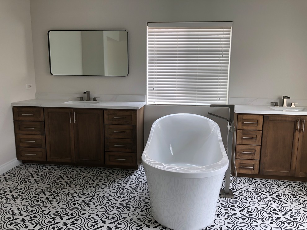 Inspiration for a large transitional master bathroom in Las Vegas with shaker cabinets, brown cabinets, a freestanding tub, an alcove shower, a one-piece toilet, white tile, subway tile, white walls, ceramic floors, an undermount sink, engineered quartz benchtops, multi-coloured floor, a hinged shower door and multi-coloured benchtops.